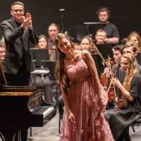 photo of pianist in pink dress smiles while bowing